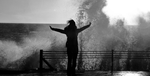 Woman facing large ocean waves